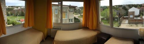 Habitación con 2 camas y 2 ventanas con cortinas de color naranja.  en Ossa Mayor Aparte en Las Gaviotas