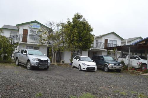 three cars parked in a parking lot in front of a building at Cabañas Hecmar in Pichilemu