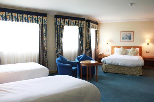 una habitación de hotel con 2 camas y una silla en Blaby Westfield Hotel, en Leicester