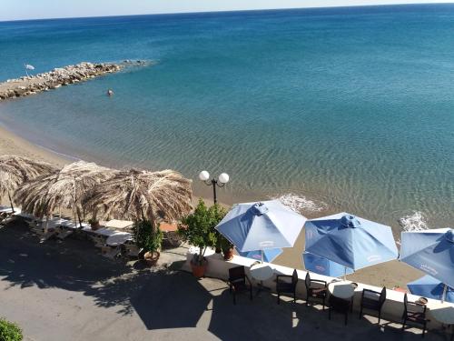 a beach with chairs and umbrellas and the ocean at San Georgio Hotel in Tsoútsouros