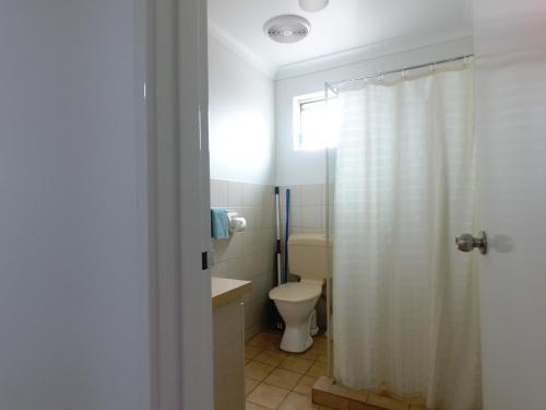 a bathroom with a toilet and a shower curtain at Esperance Bay Holiday Park in Esperance