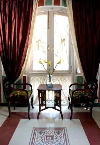 a living room with two chairs and a table and a window at Casa Anjuna in Anjuna