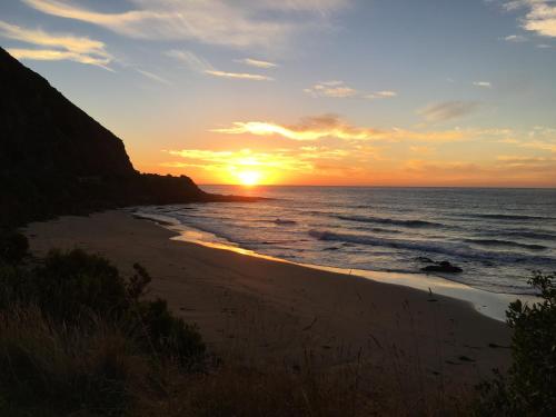 a sunset on a beach near the ocean at Cumberland River Holiday Park in Lorne