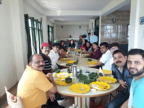 a group of people sitting around a table eating at Trimurti Pine Valley Resort in Shimla