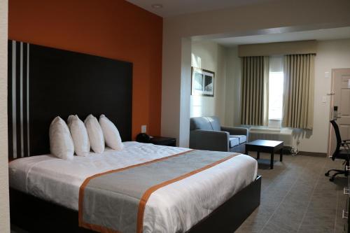a hotel room with a bed and a living room at Scottish Inn & Suites - IAH Airport in Humble