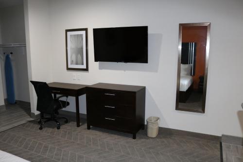 a room with a desk and a television on a wall at Scottish Inn & Suites - IAH Airport in Humble