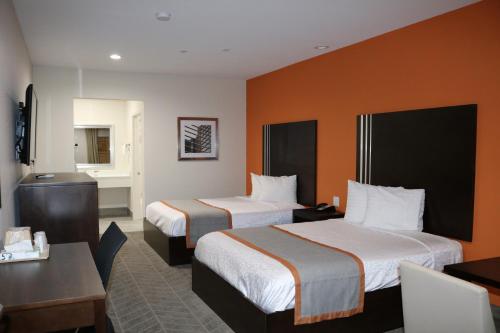 a hotel room with two beds and a desk at Scottish Inn & Suites - IAH Airport in Humble