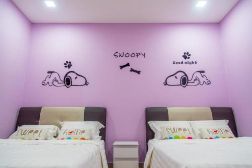 two beds in a room with a purple wall at Lavender One Residence Apartment in Sekincan
