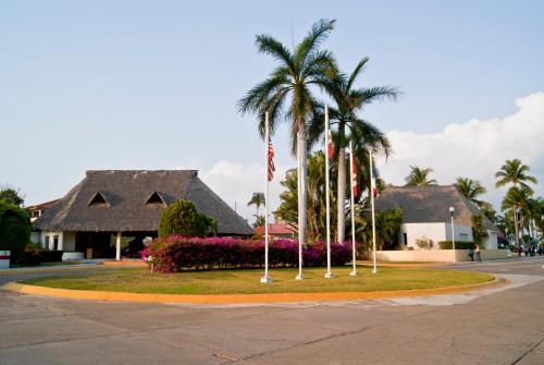 a park with palm trees and flowers in front of a house at Qualton Club Ixtapa All Inclusive in Ixtapa