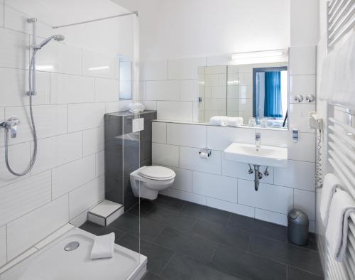 a white bathroom with a toilet and a sink at Hotel Weidenhof in Regensburg