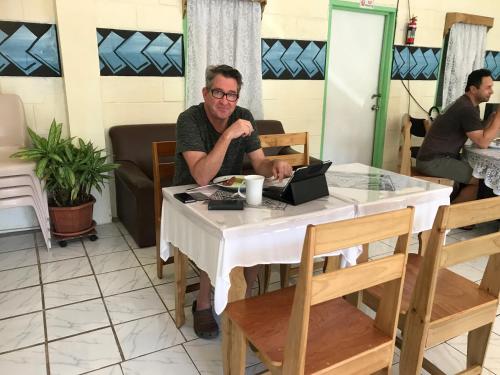 a man sitting at a table with a laptop at Moatoga Hotel in Apia