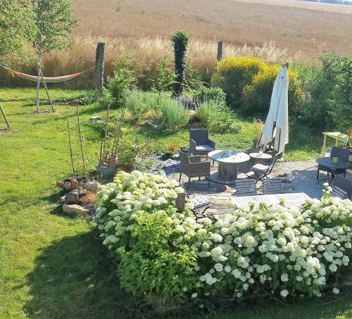 a garden with a table and an umbrella and flowers at Le Briou in Précy