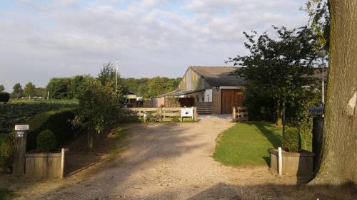 a house with a dirt road in front of a yard at Camping en vakantiewoning 'Ut Tumpke' in Kessel