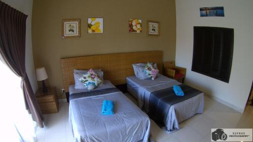 two beds in a room with blue pillows on them at ZamLan Gold Coast Morib Intl Resort - Studio in Banting