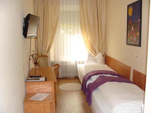 a bedroom with a bed and a television and a window at Hotel Löhr in Baden-Baden