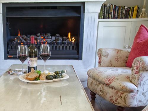 a table with a plate of food and two glasses of wine at Auberge Clermont in Franschhoek