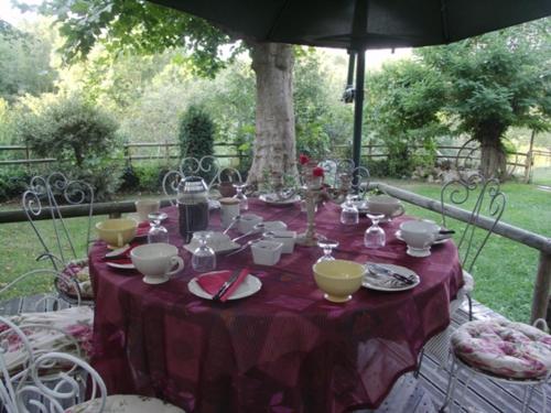 Una mesa con un mantel morado y cuencos y tazas. en Haras Picard du Sant, en Lasserre