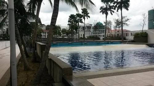 a swimming pool with palm trees in front of a building at Garden Apartment at Zenith in Petaling Jaya
