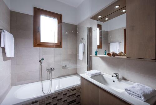 a bathroom with a bath tub and a sink at Oikos- "Your Cretan House" in Angeliana