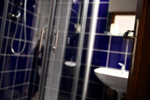 a blue tiled bathroom with a sink and a shower at Giotto Apartments in Prague