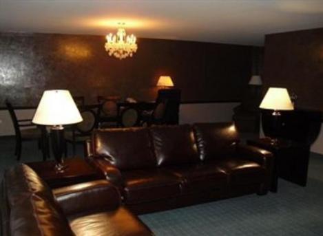 a living room with a brown leather couch and two lamps at Causeway Bay Hotel in Lansing