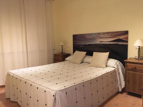 a bedroom with a large white bed with a painting on the wall at Medano Beach - MARINEDA - Pool View - 2 in El Médano
