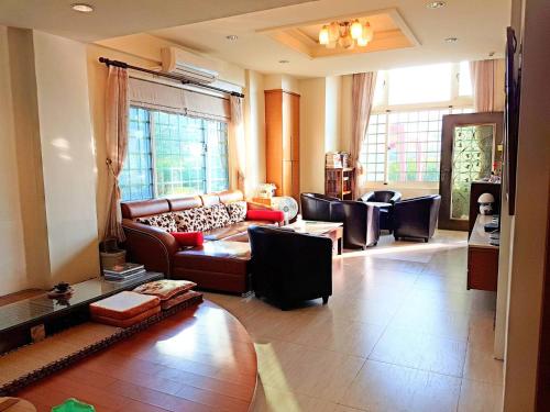 a living room with a couch and chairs and windows at Emerald Grange in Gongguan