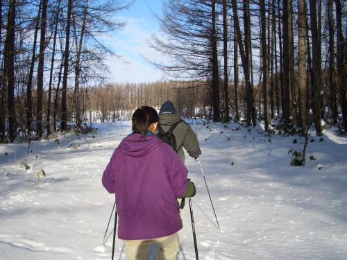 two people are cross country skiing in the snow at Akane-yado in Nakafurano