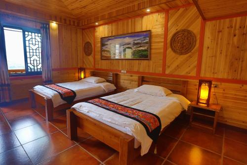 two beds in a room with wooden walls at Longji Holiday Hotel in Longsheng