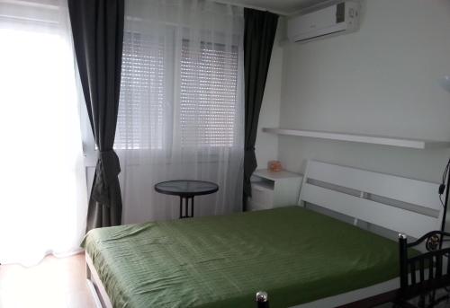 シオーフォクにあるAranyhíd Ilona Apartmanのベッドルーム(緑のベッド1台、窓付)