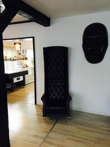 a black chair sitting in a room with a mirror at Hotel Ammerland garni in Wilhelmshaven