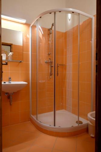 an orange bathroom with a shower and a sink at Giotto Apartments in Prague