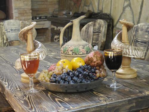 a bowl of fruit on a table with two wine glasses at Family Hotel Mountain Scream in Tbilisi City