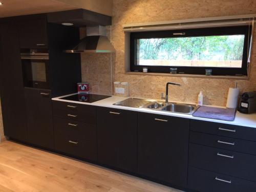 a kitchen with black cabinets and a sink and a window at Abarolodge in Hannut