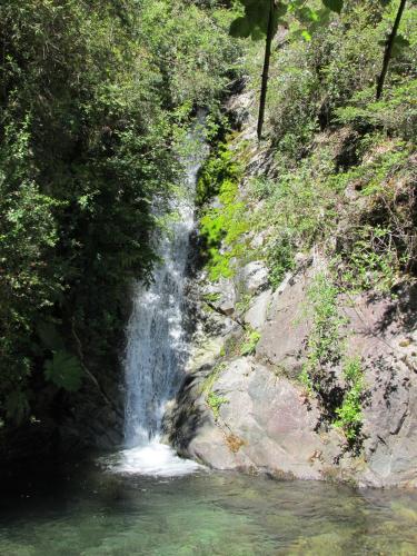 a waterfall on the side of a mountain next to a river at Cabanas L'ESCALE in Coñaripe