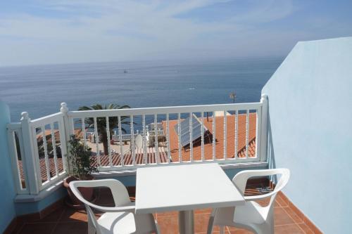 プエルト・デ・サンティアゴにあるÁtico Los Ángeles Min 3 nightsの白いテーブルと椅子が備わるバルコニーと海