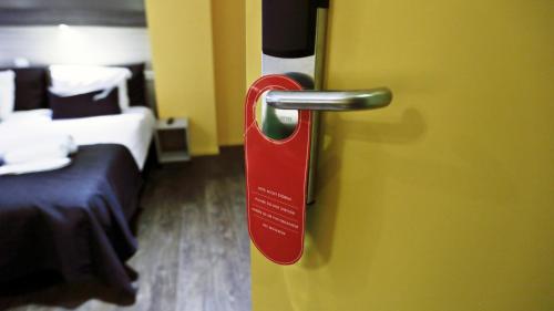 a red door handle in a room with a bed at City Hotel Amsterdam in Amsterdam