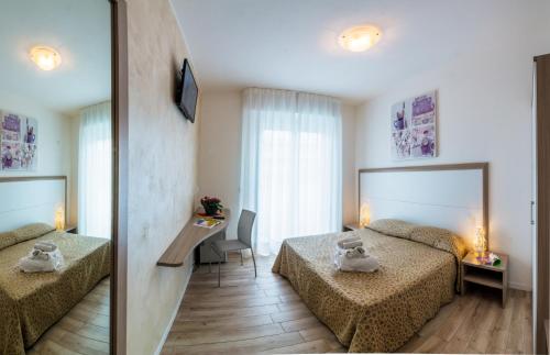 a hotel room with two beds and a mirror at Hotel Milano 3S in Bibione