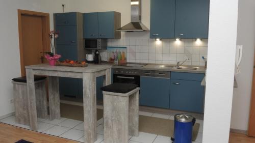 a kitchen with blue cabinets and a table with a bowl of fruit at Ferienwohnung Wössner in Oberndorf