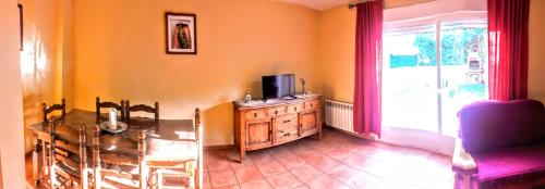 a living room with a television and a table and chairs at Parque Sierra Norte in Rascafría