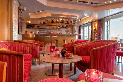 a restaurant with red chairs and tables and a bar at Romantik Hotel Säntis in Appenzell