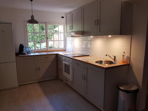 a kitchen with white cabinets and a sink and a window at Maison Provencale in Cavalaire-sur-Mer