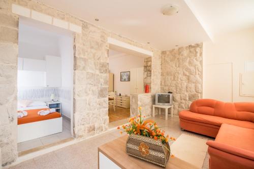 Friendly Apartments في Gruda: غرفة معيشة مع أريكة برتقالية وغرفة نوم