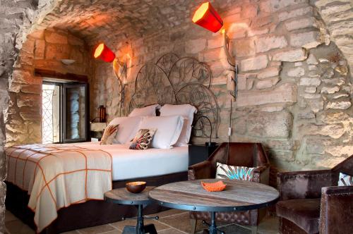 a bedroom with a bed and a stone wall at La Maison du Passage - Chambres - Suites premium, Spa, Piscine et Restaurant in Martignargues