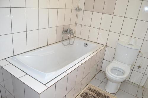 a white bathroom with a tub and a toilet at Massao Palace Hotel in Yaoundé