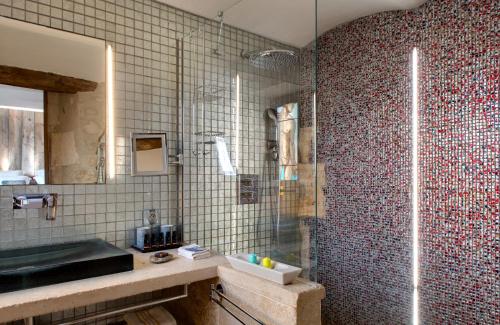 a bathroom with a glass shower and a sink at La Maison du Passage - Chambres - Suites premium, Spa, Piscine et Restaurant in Martignargues