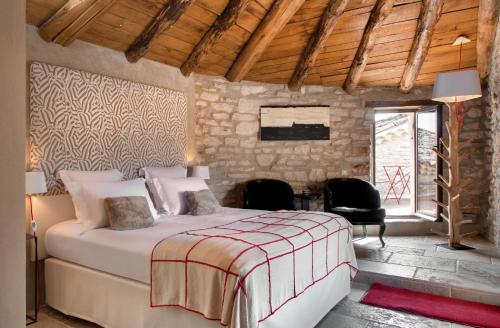 a bedroom with a bed and a stone wall at La Maison du Passage - Chambres - Suites premium, Spa, Piscine et Restaurant in Martignargues