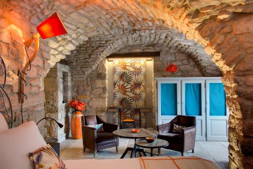 a room with chairs and a table in a stone wall at La Maison du Passage - Chambres - Suites premium, Spa, Piscine et Restaurant in Martignargues