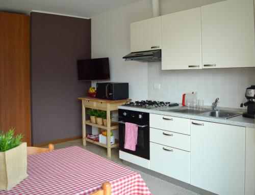 a kitchen with white cabinets and a stove top oven at Como's Lake Mountains B&B in Cremeno