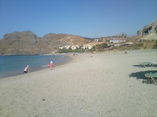 a couple of people walking on a beach at Zefyros Studios in Damnoni